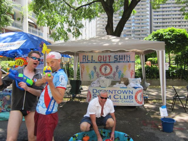 Hot enough?  Downtown Swim Club members cooling off passers-by with a bit of water in front of their booth.